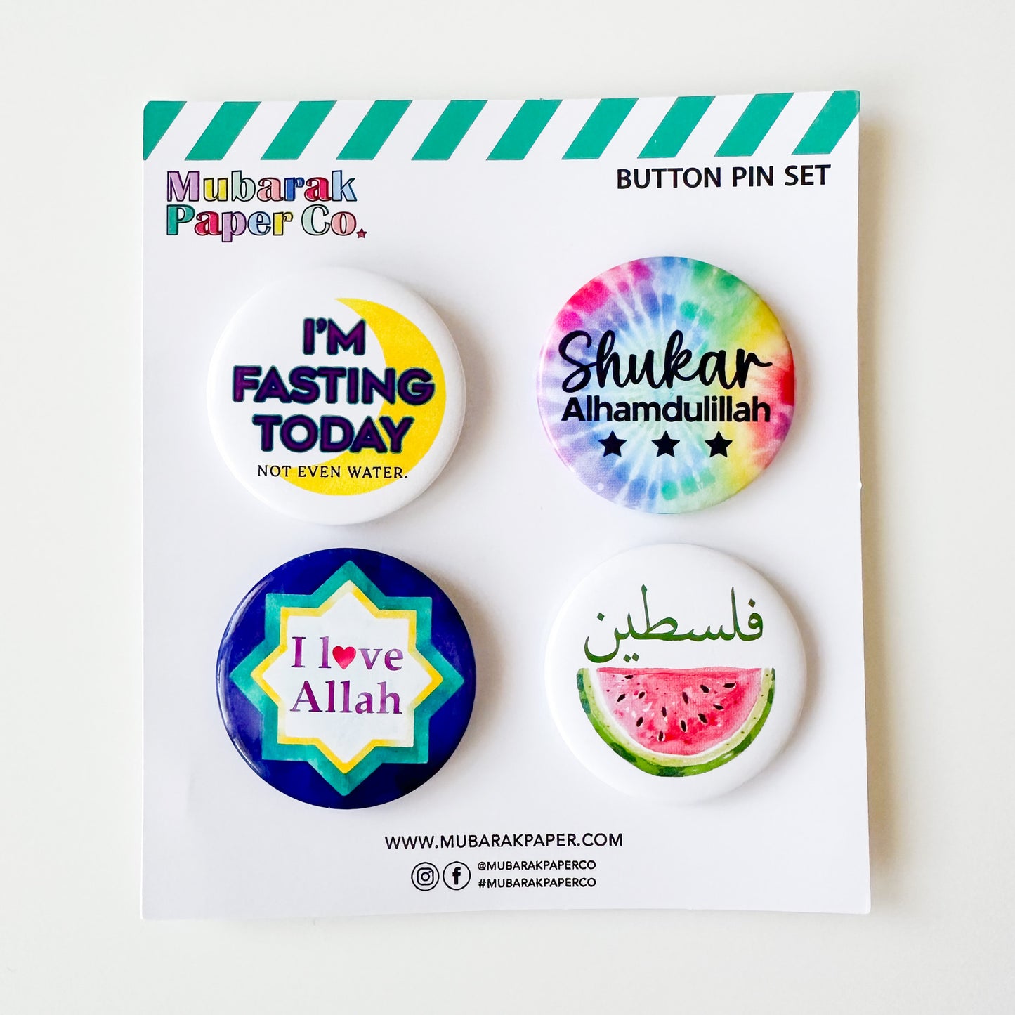 Set of four colorful buttons with text on a Mubarak Paper Co. card.