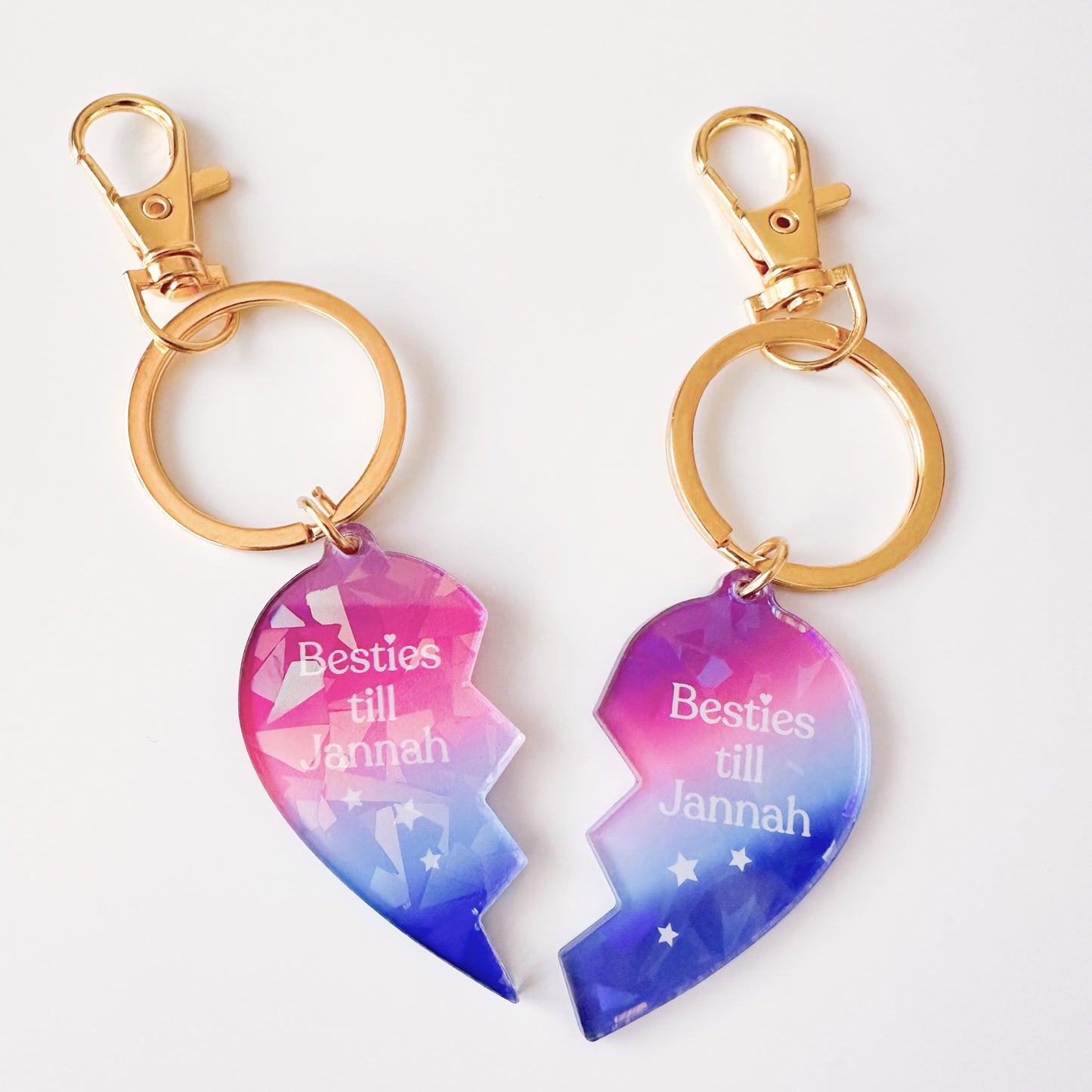 Two heart-shaped keychains with gold hooks, one pink and one blue, featuring the text 'Besties till Jannah' on a white background.