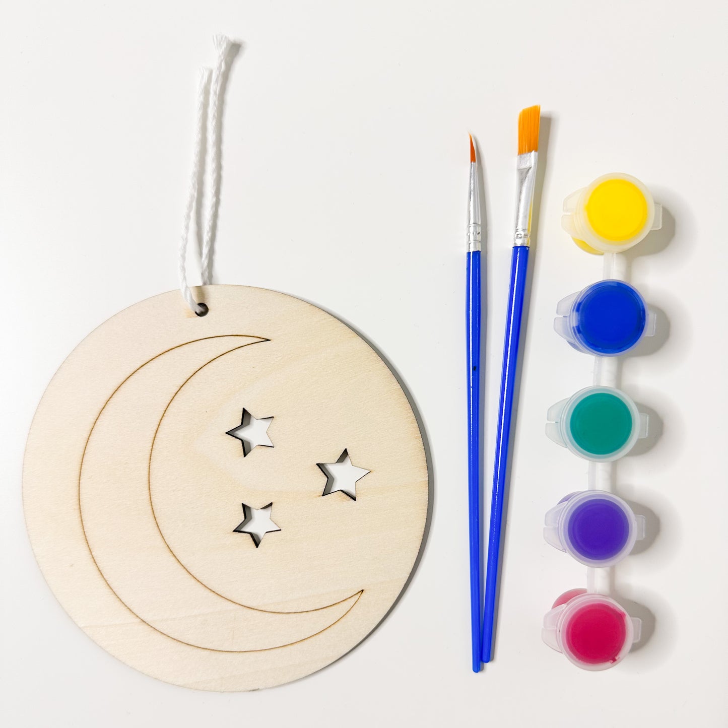 Wooden ornament with cut-out stars, paintbrushes, and paint containers on a white background
